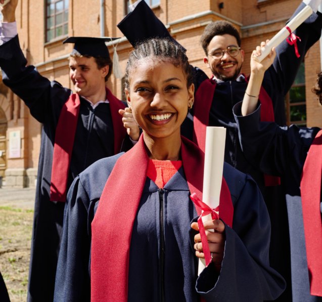 Portrait of happy graduated student with diploma smiling at camera with her friends celebrating graduation in background